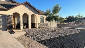 A house with a stone facade, arched entryway, and a landscaped front yard with a tree. - Quiet, Cozy Three Bedroom Two Bath Home, Great Location (Page)