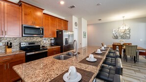 A modern kitchen with granite countertops, stainless steel appliances, and wooden cabinets. - Town Home With Pool in Gated Golf Community Of Champions Gate Resort (Davenport)