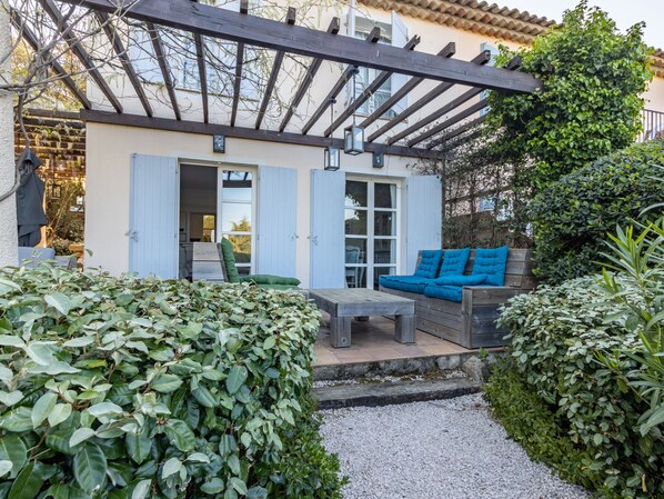 A covered outdoor seating area with a wooden bench and a blue sofa.