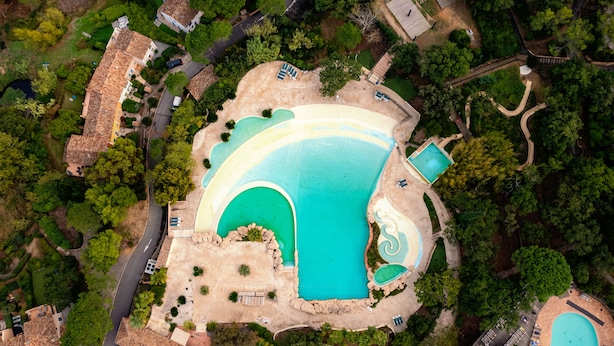 Ein Luftbild eines Resorts mit einem großen zentralen Pool, mehreren kleineren Pools und einem gewundenen Weg.