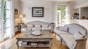 Ein Wohnzimmer mit einer Couch, einem Couchtisch mit Büchern, einer Lampe und einem gerahmten Foto an der Wand.
