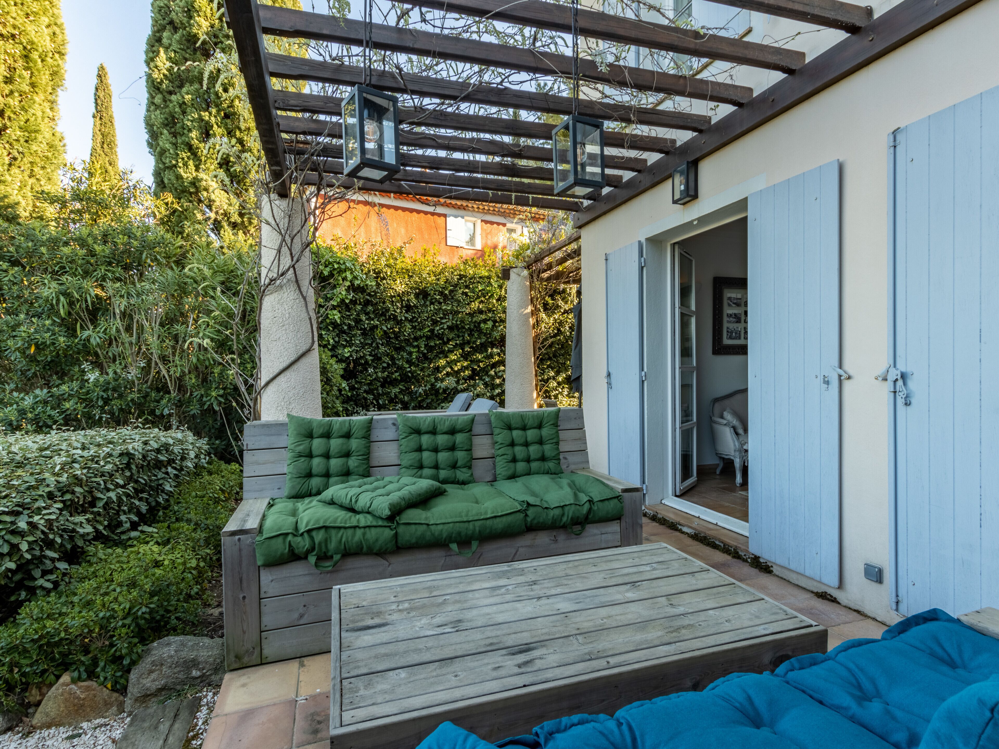 A wooden deck with a green cushioned bench and a blue cushioned sofa.