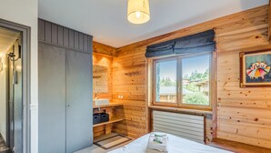 Una habitación de cabaña de madera con una cama, una ventana, un lavabo y una puerta.