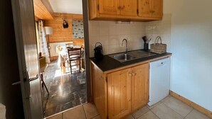 Cocina compacta con armarios de madera, un fregadero y lavavajillas.