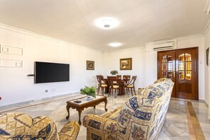 A living room with a sofa, chairs, a coffee table, a TV, and a dining table.