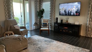 A living room with a sofa, armchair, and a fireplace. There is a television mounted on the wall and a potted plant. - in Glendale Near stadium, entertainment & shopping (Glendale)