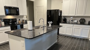 A modern kitchen with a central island, white cabinetry, a black refrigerator, and a microwave. - in Glendale Near stadium, entertainment & shopping (Glendale)