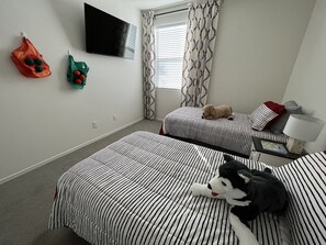 A hotel room with two beds, a flat-screen TV, a window with patterned curtains, and a nightstand with a lamp. - in Glendale Near stadium, entertainment & shopping (Glendale)