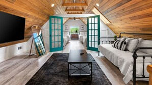 A loft-style bedroom with a large bed, a sofa, a TV, and a wooden ceiling. - Elegant Birdhouse Cabin with 🔥Heated🔥 Cowboy Pool (Kyle)