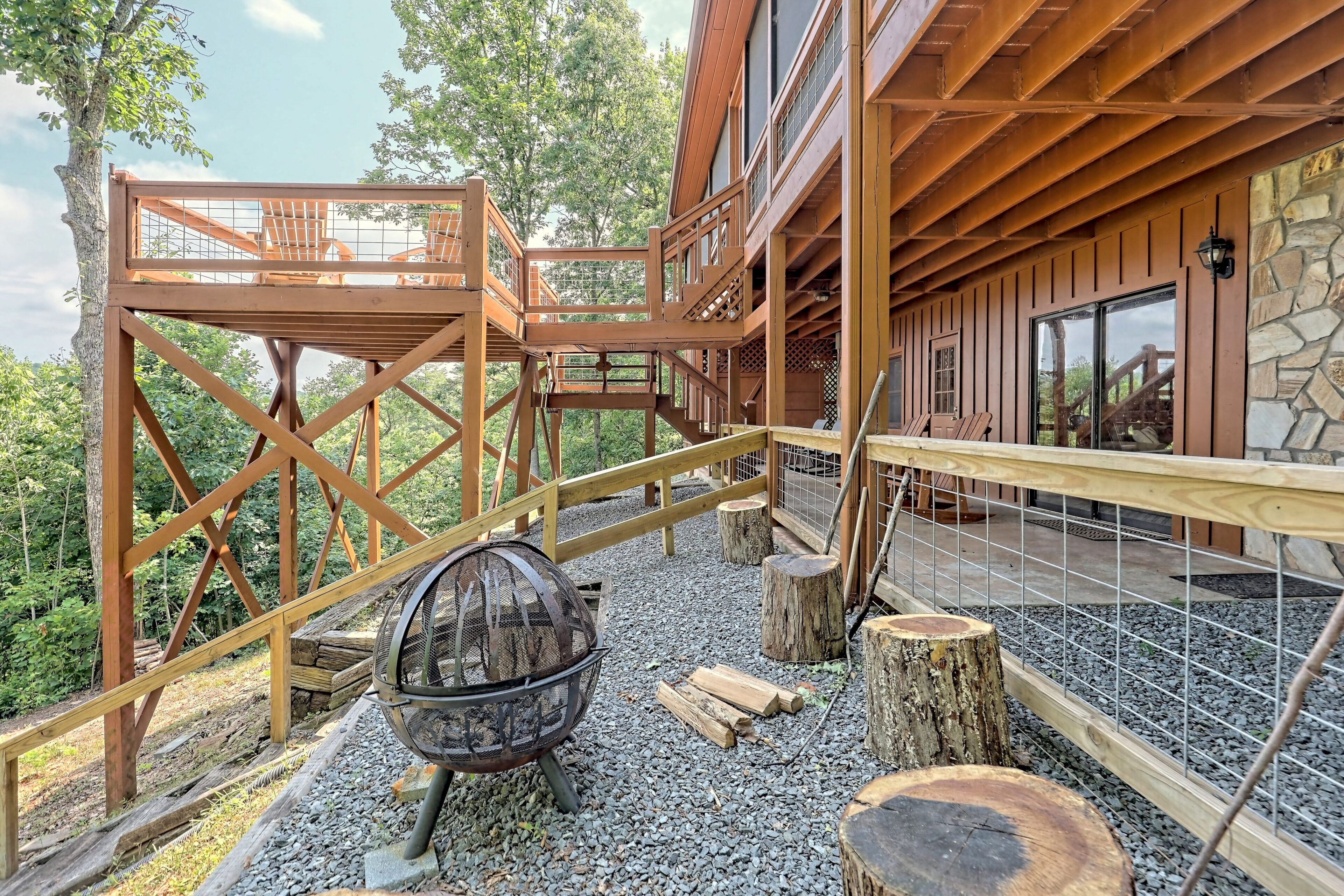Eine Holzterrasse mit Feuerstelle, Holzeingang und einer Steinsäule.