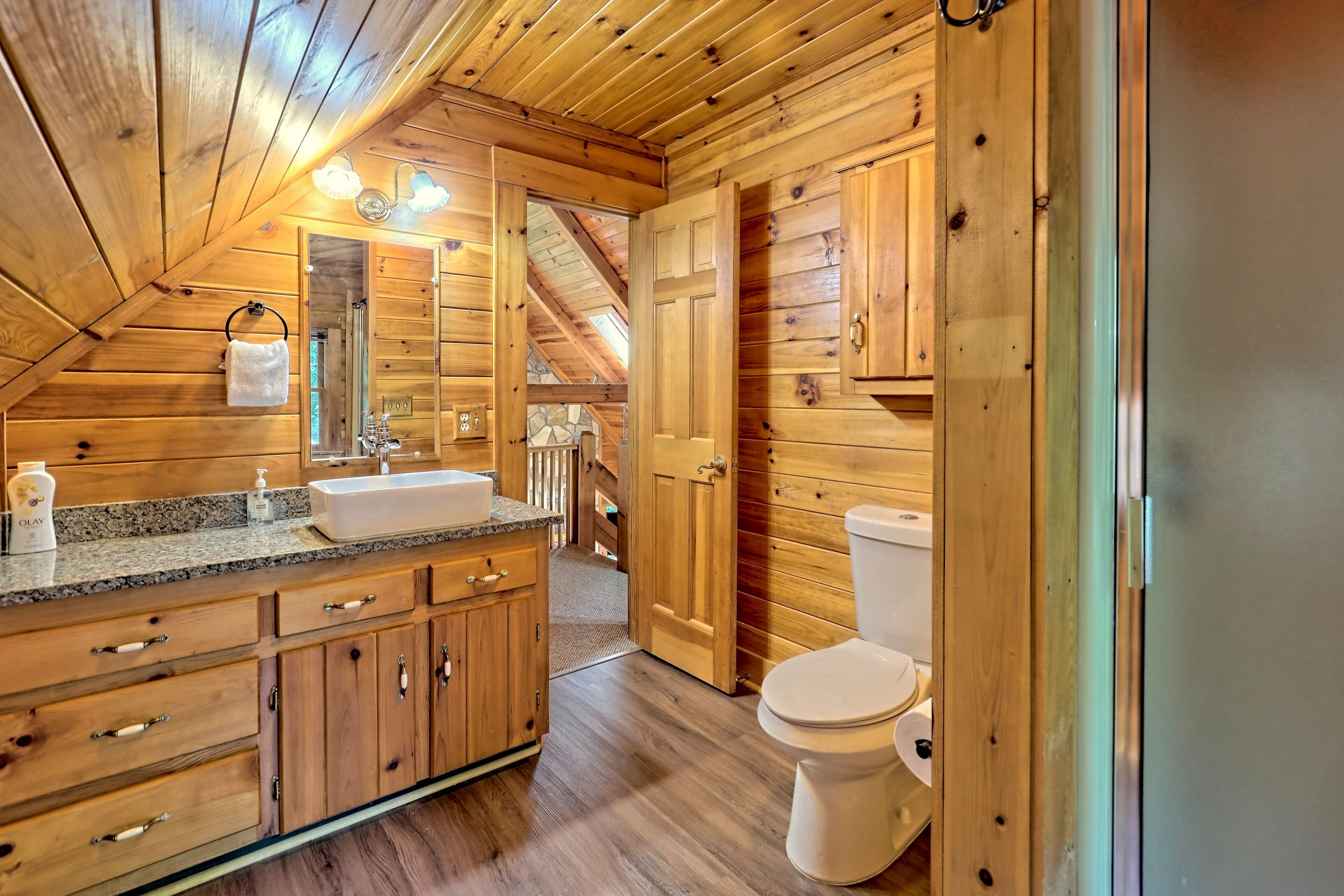 Baño de una cabaña de madera con lavamanos, espejo y retrete.