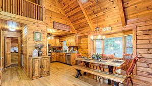 A wooden cabin interior with a dining area, kitchen, and a 'welcome' sign. - Large Deck, Screened Porch, Hot Tub, Fire Pit (Morganton)