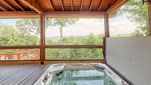 A hot tub on a wooden deck with a view of a forest and mountains. - Large Deck, Screened Porch, Hot Tub, Fire Pit (Morganton)