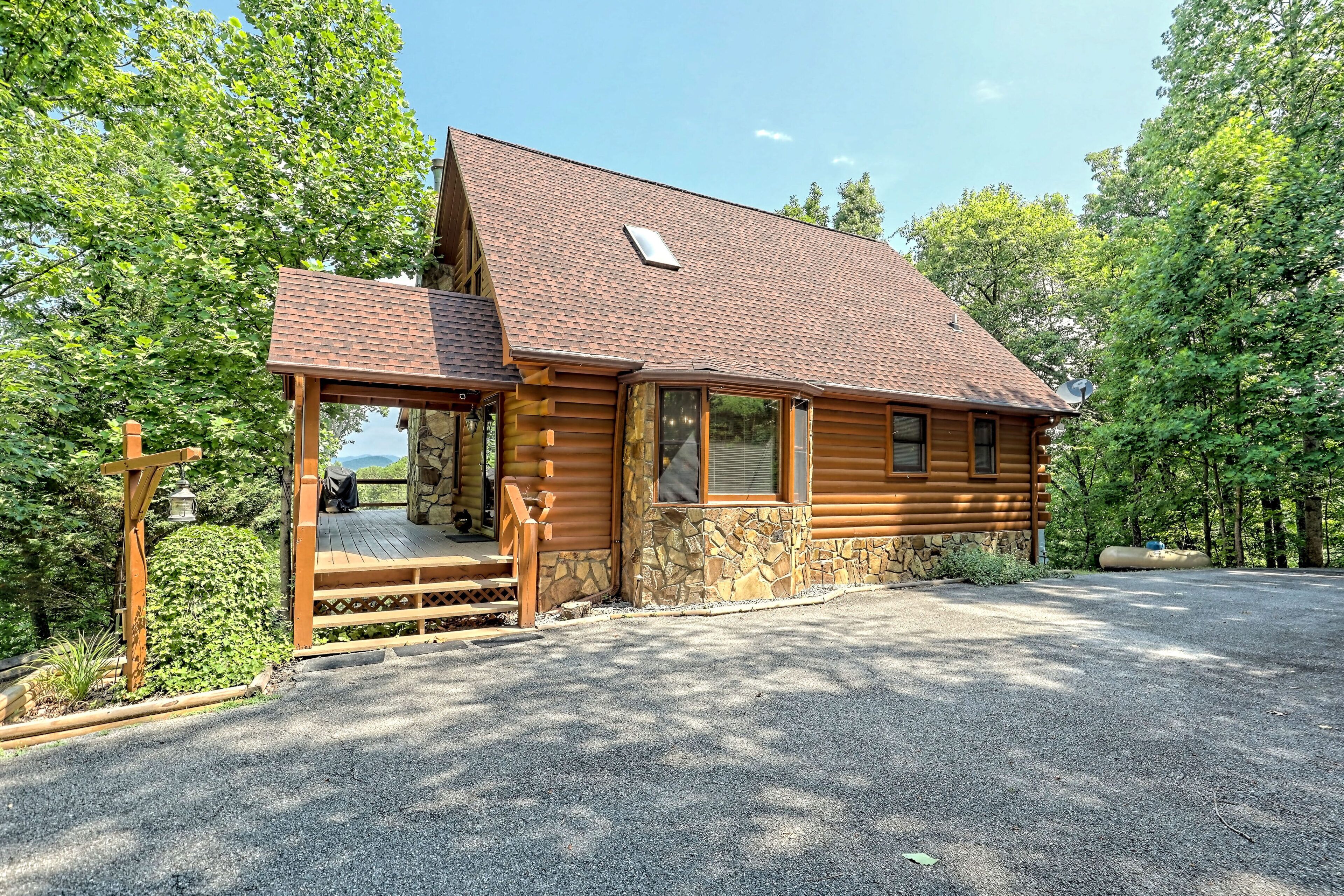 A log cabin with a stone foundation, a wooden porch, and a satellite dish.