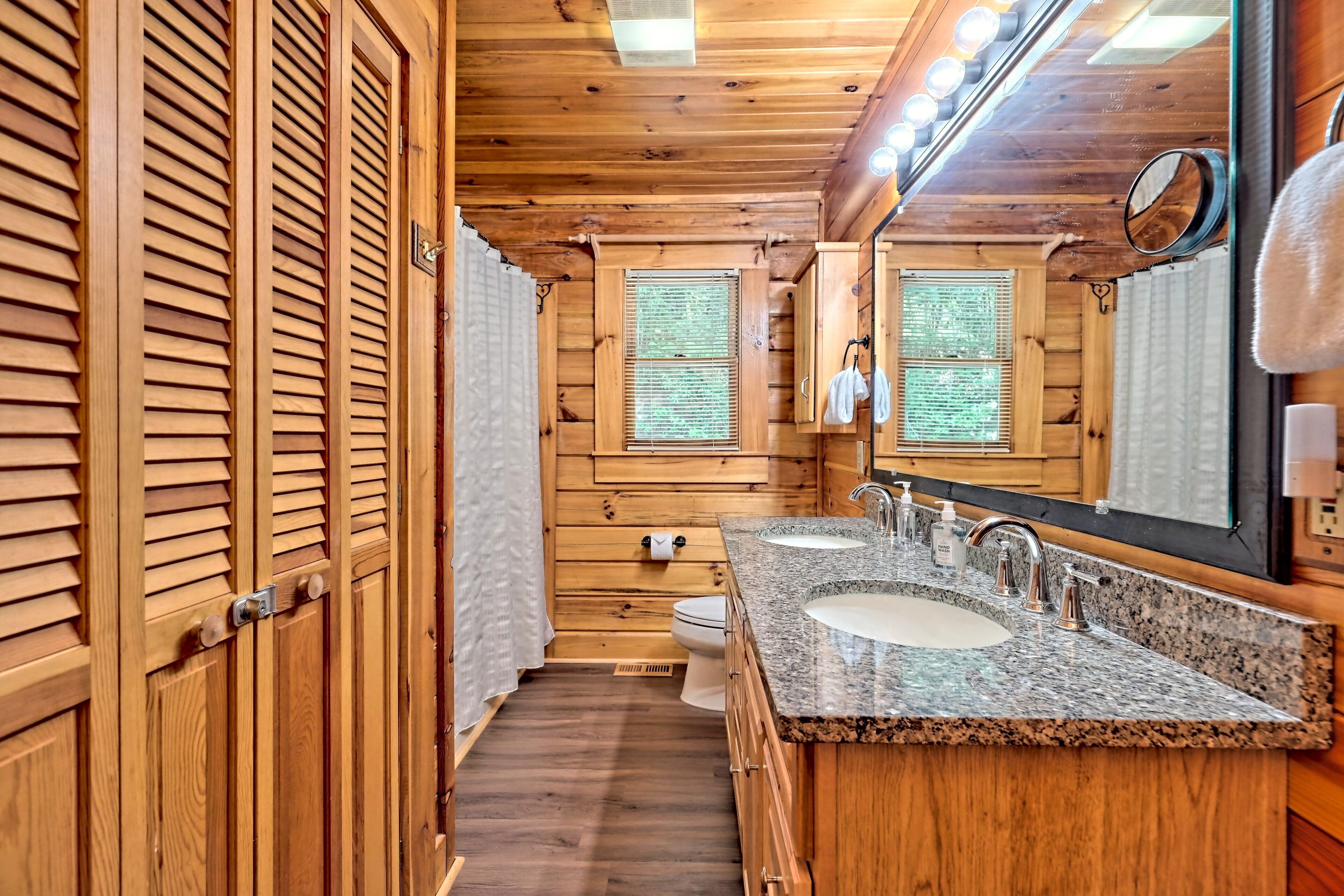 A wooden cabin bathroom with two sinks, a large mirror, and a shower area.