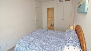 Een slaapkamer met een bed, een kledingkast en een badkamer die door een open deur zichtbaar is.