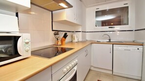 Een kleine keuken met een magnetron, fornuis en vaatwasser.