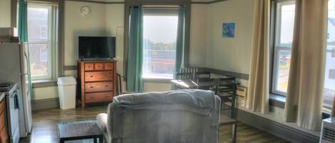 A compact living space with a sofa, a television, a dining table, and a kitchen area.