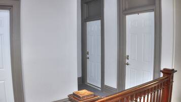A hallway with two white doors, a wooden handrail, and a carpeted floor.