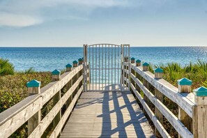 A wooden boardwalk leading to a gate with a view of the ocean.