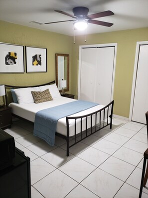 A bedroom with a bed, a ceiling fan, a nightstand, a mirror, and two framed pictures on the wall. - Wynwood Miami Tropical Hideaway Guest Suite (Miami)