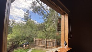A wooden bench with a view of a backyard, a wooden fence, and a barbecue grill.