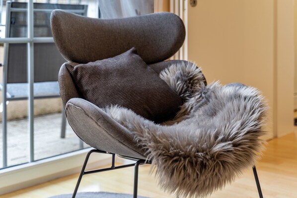 A modern chair with a fur throw and a cushion.