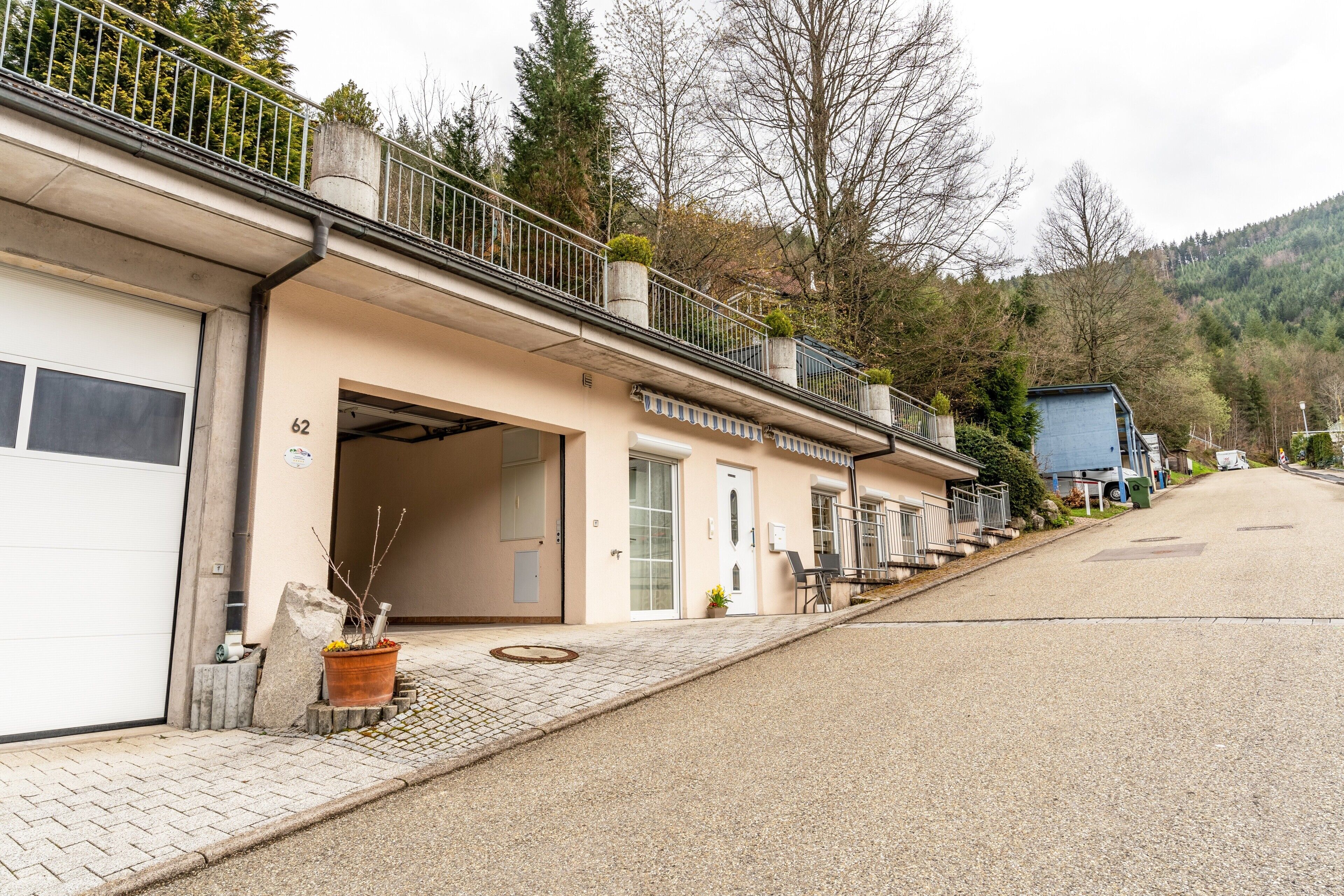 Une rangée de bâtiments, chacun doté d’une porte de garage, d’un petit espace extérieur aménagé en coin salon et d’un escalier menant à un balcon.