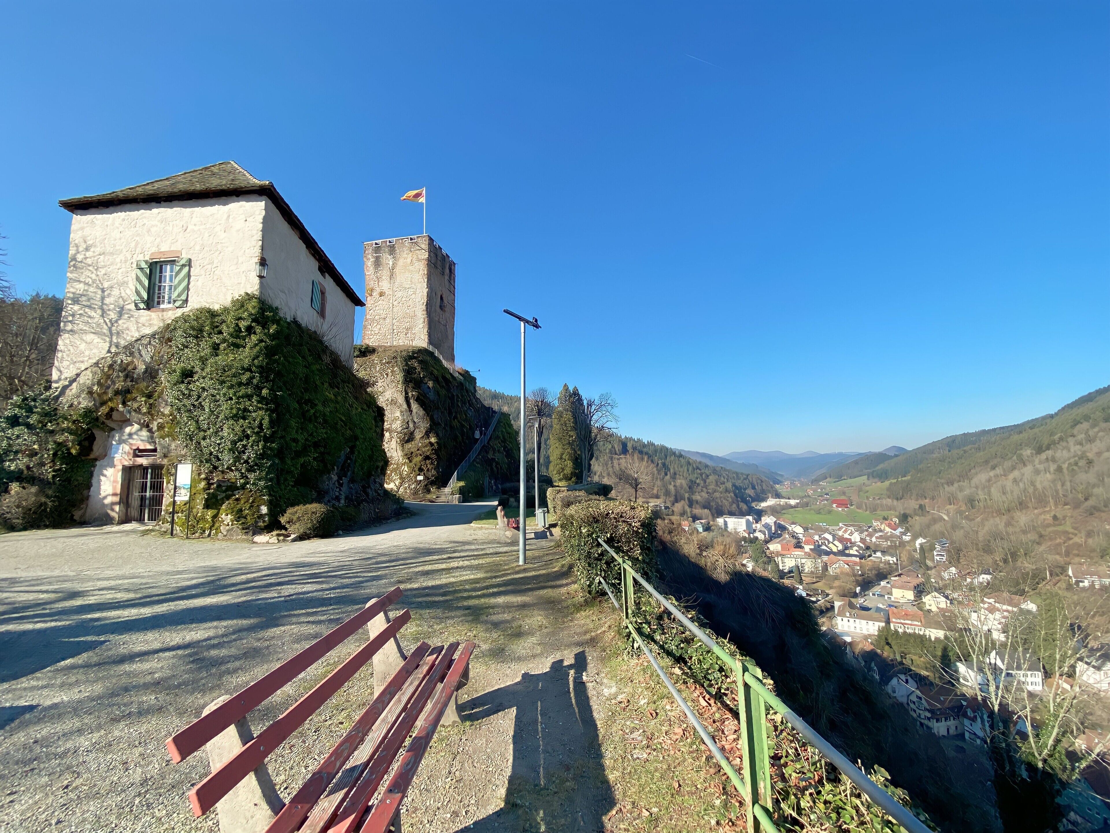 A historic building with a tower, a paved pathway, and a bench.