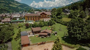 A mountain village with traditional buildings, a central courtyard, and a view of the surrounding hills.