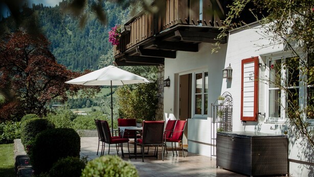 A patio with outdoor seating, a table, and chairs.