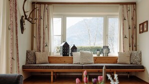 A cozy room with a large window, a wooden bench, and a view of mountains.