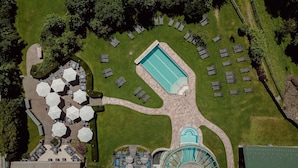 An aerial view of a resort with a swimming pool, sun loungers, and outdoor seating areas.