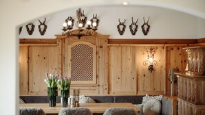 A wooden dining area with a high wooden bench, a table with chairs, and wall-mounted deer skulls.