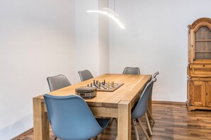 A dining area with a wooden table, blue chairs, a chessboard, and a wooden cabinet.