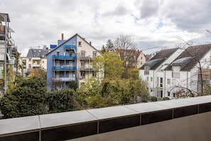 A residential building with multiple balconies, a mix of architectural styles, and a view of neighboring houses.