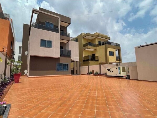 Un edificio moderno de varios pisos con terraza plana y un equipo médico en la planta baja.