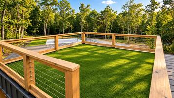 A wooden deck with a grassy area, surrounded by trees.
