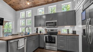 A modern kitchen with grey cabinets, stainless steel appliances, and a wooden ceiling. - Menlo GA Tiny Home Experience! Beautiful Drive (Menlo)