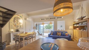 A spacious living area with a wooden dining table, a blue sofa, and a bookshelf. - Cavalaire sur mer Mas Boubanette (CAVALAIRE SUR MER)