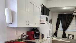 A compact kitchen with white cabinets, a microwave, a coffee maker, and a small refrigerator. - Private studio with working space, in Lake Worth Beach (Lake Worth)