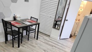 A modern living room with a sofa, a dining table with chairs, a kitchen area with a refrigerator, and a sliding door closet. - Private studio with working space, in Lake Worth Beach (Lake Worth)