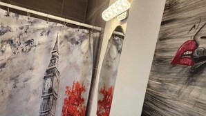 A bathroom with a large mirror, a sink, and a shower curtain depicting a famous tower and autumn leaves. - Private studio with working space, in Lake Worth Beach (Lake Worth)