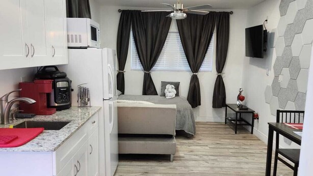 A compact room with a kitchenette, a bed, a small table, and a TV. - Private studio with working space, in Lake Worth Beach (Lake Worth)