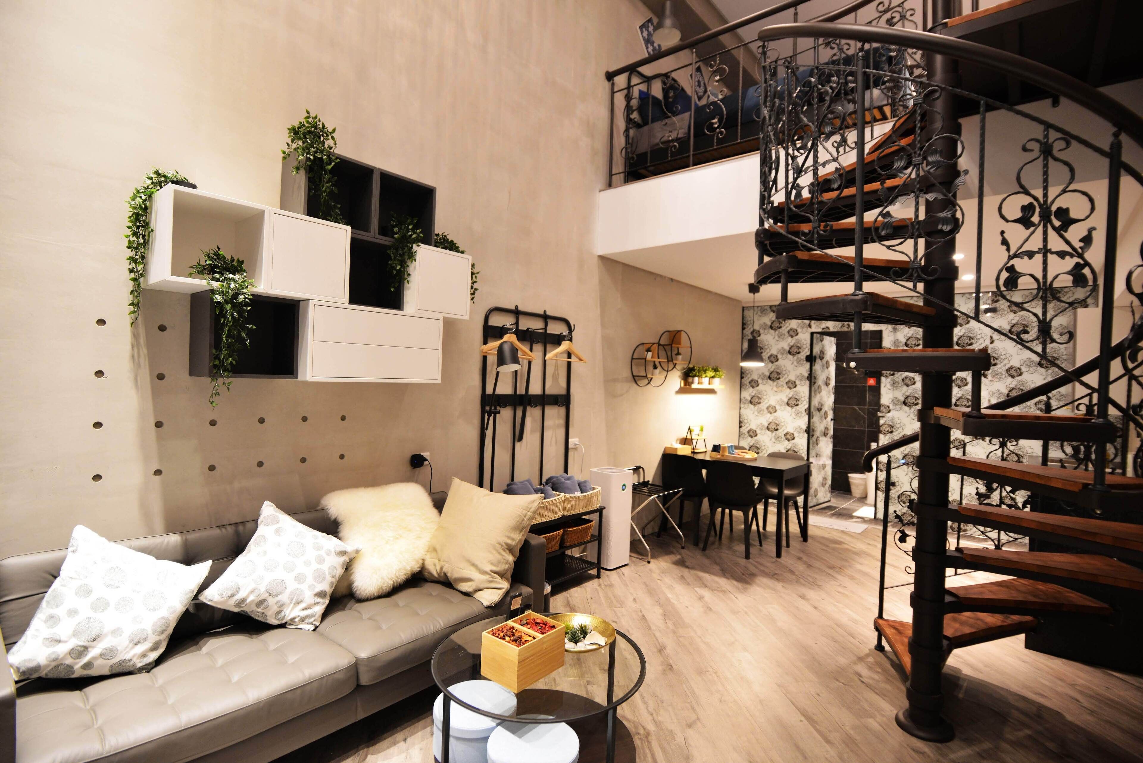 A modern living room with a sofa, coffee table, and a spiral staircase.