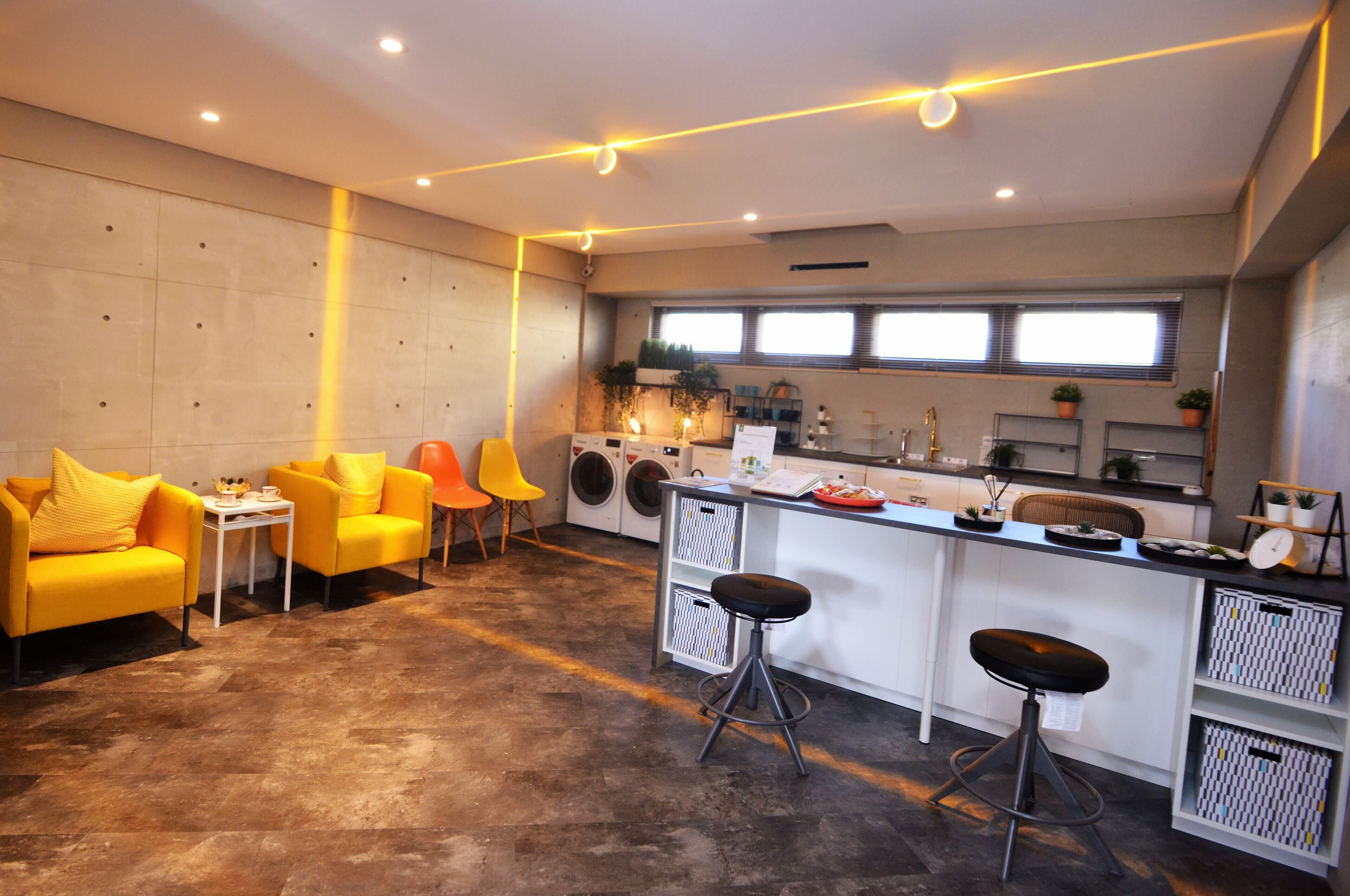 A modern kitchen with a bar area, yellow chairs, and a washing machine.