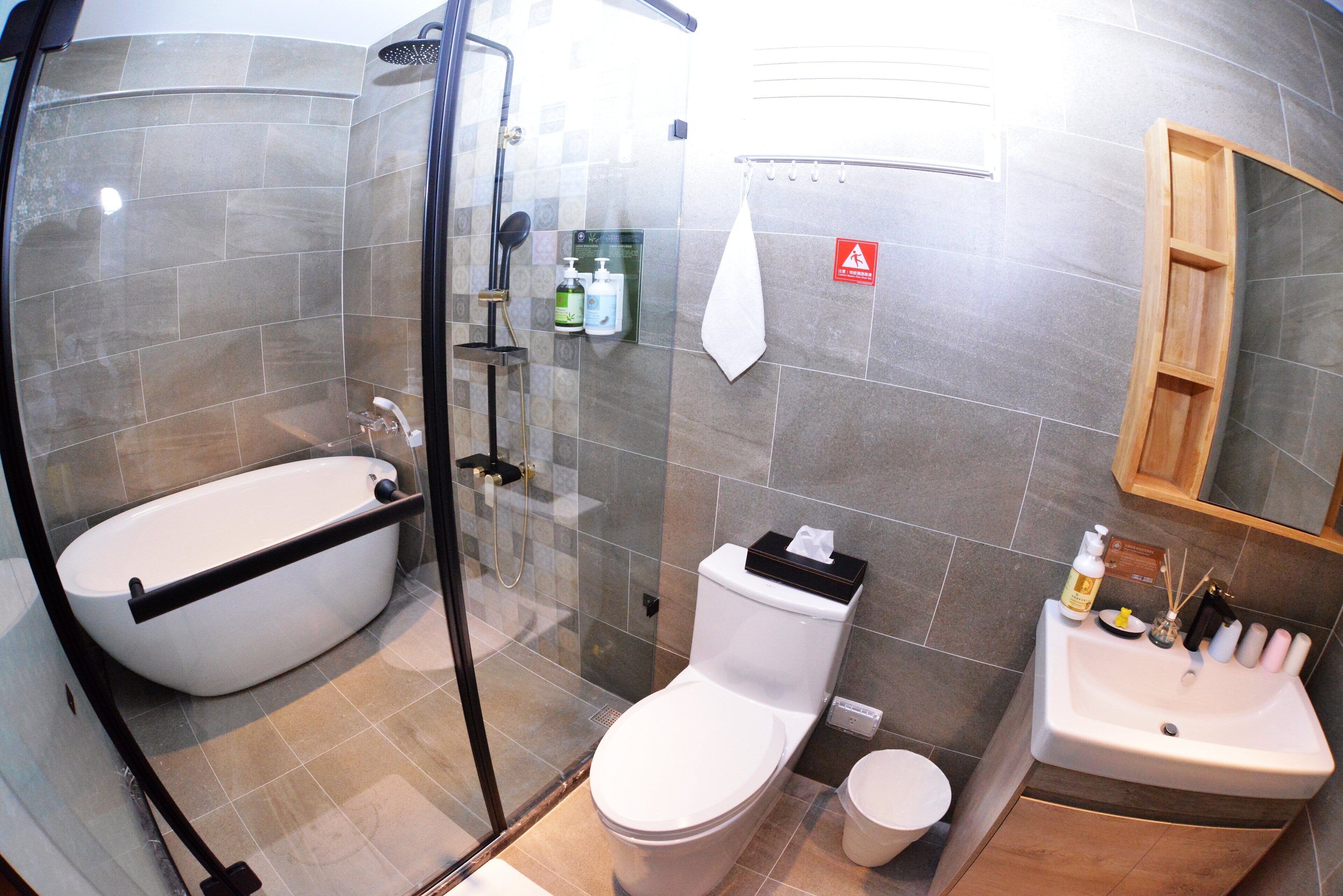 Een moderne badkamer met een douchecabine van glas, een wit toilet en een wastafel met toiletartikelen.