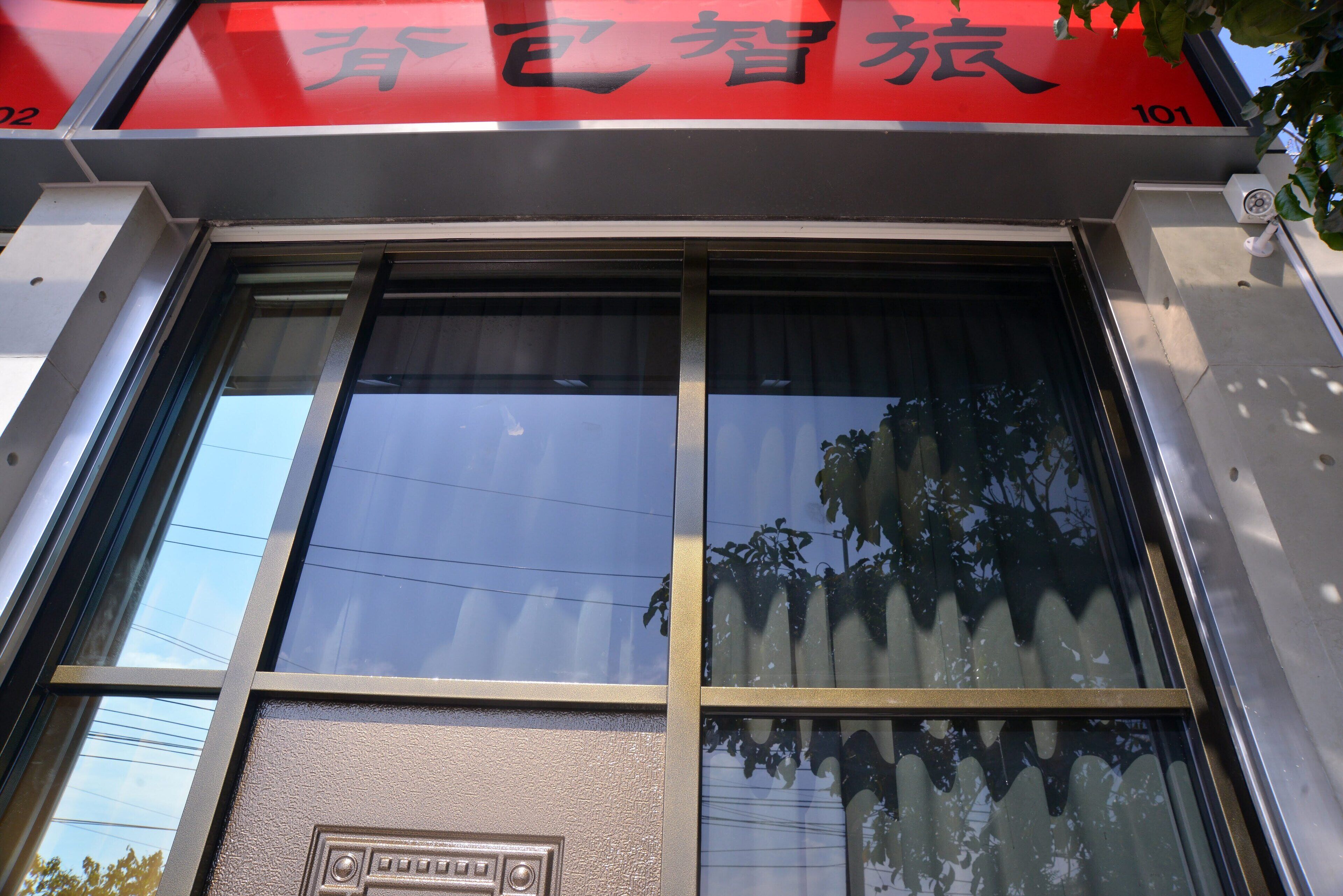 A building facade with large windows and a red sign with Chinese characters.