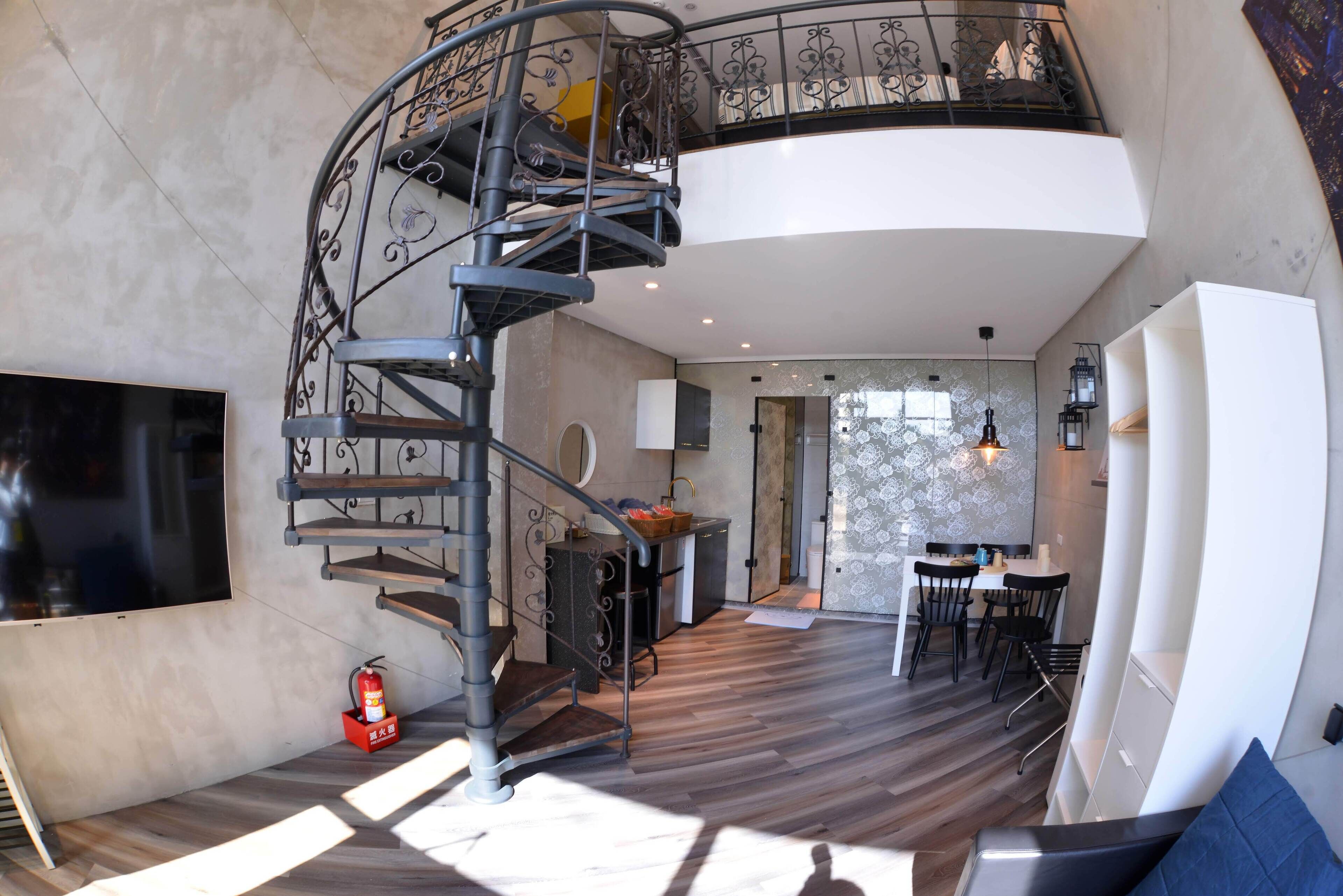 A modern interior with a spiral staircase, a dining area, and a kitchen.