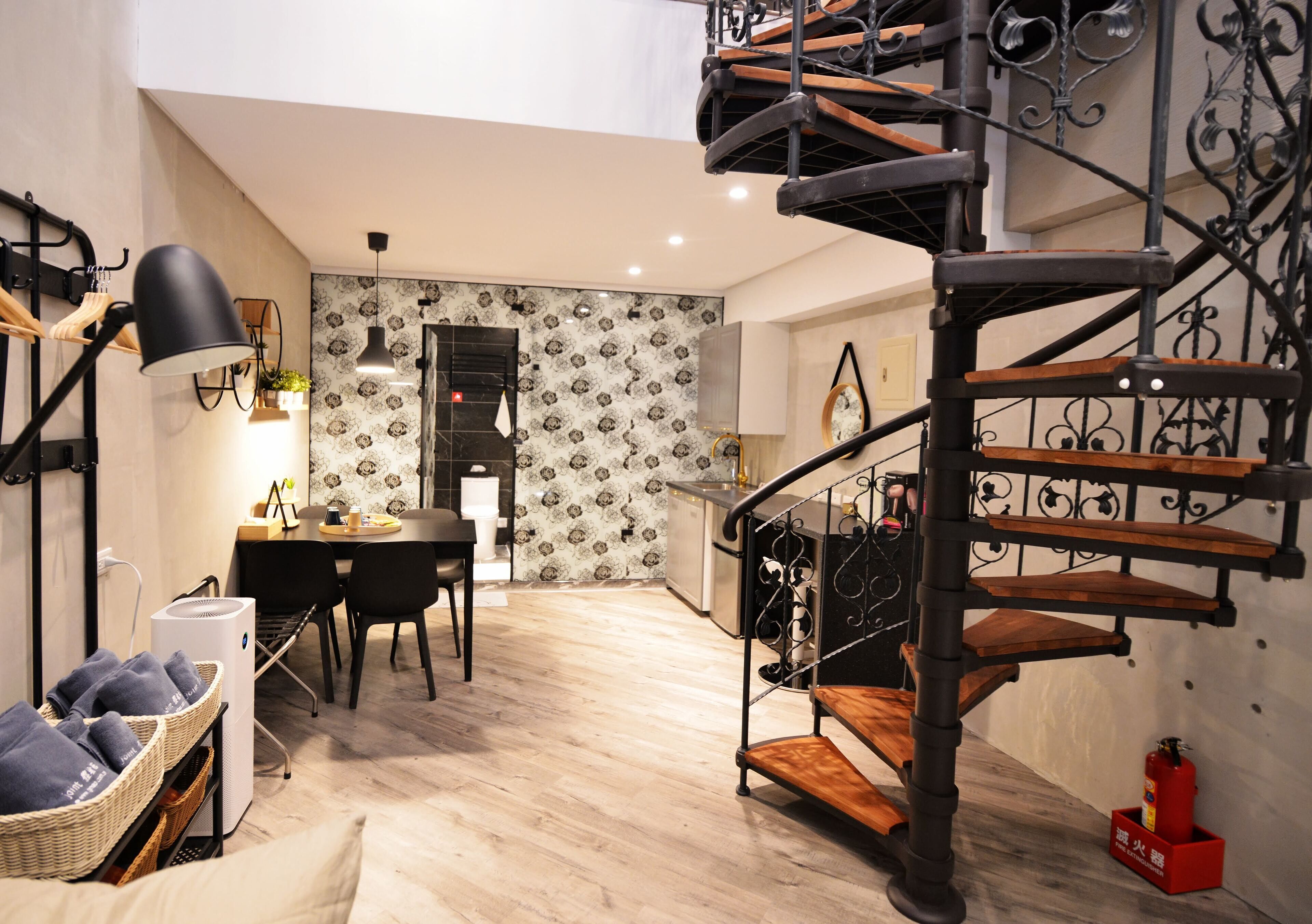 Een moderne keuken met een eethoek, een trap en een kleine eettafel met stoelen.